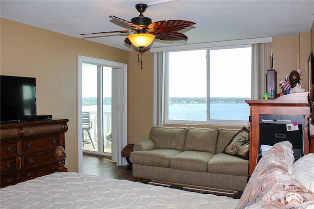 bedroom featuring access to outside, a water view, ceiling fan, and wood finished floors