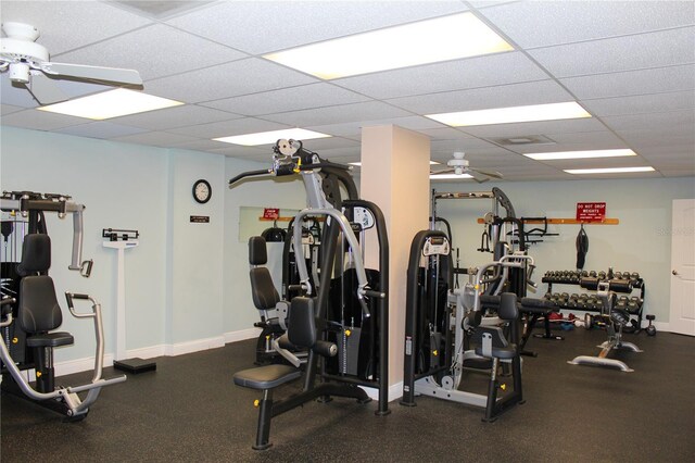 workout area with baseboards, a drop ceiling, and a ceiling fan