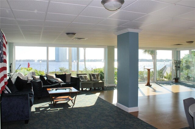 living area with floor to ceiling windows, visible vents, a water view, wood finished floors, and a drop ceiling