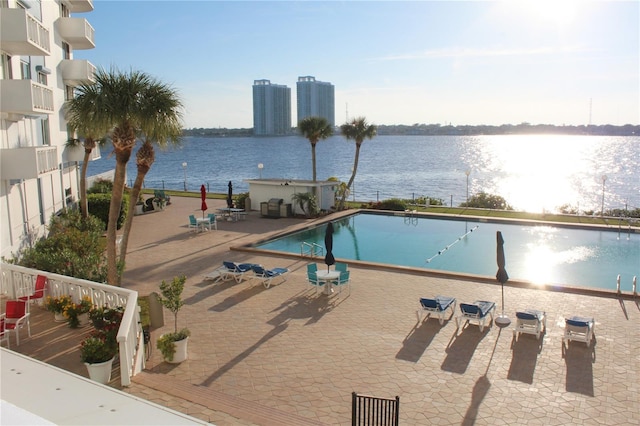 pool featuring a water view and a patio area