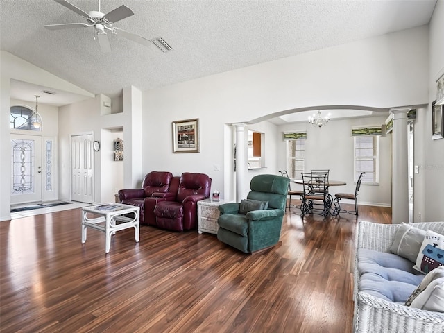 living area with dark wood-style floors, ceiling fan with notable chandelier, visible vents, and ornate columns