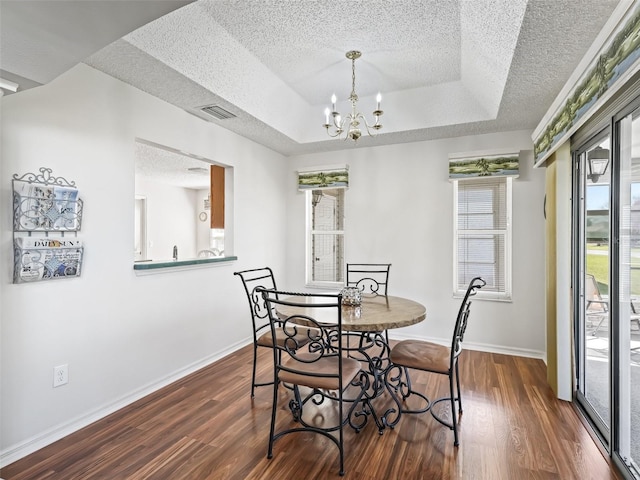 dining room featuring a textured ceiling, a tray ceiling, and dark wood-style flooring