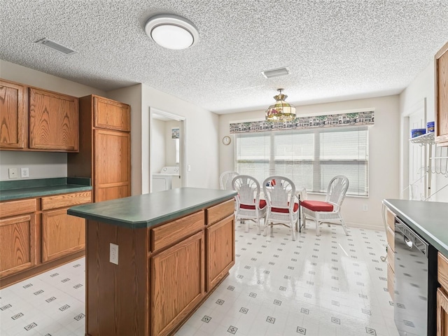 kitchen with washing machine and dryer, visible vents, dishwasher, light floors, and dark countertops