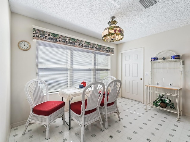 dining space with visible vents, a textured ceiling, and tile patterned floors