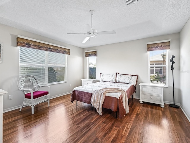 bedroom with visible vents, a textured ceiling, baseboards, and wood finished floors