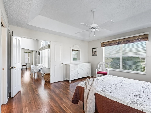 bedroom with ceiling fan, baseboards, dark wood finished floors, and a textured ceiling