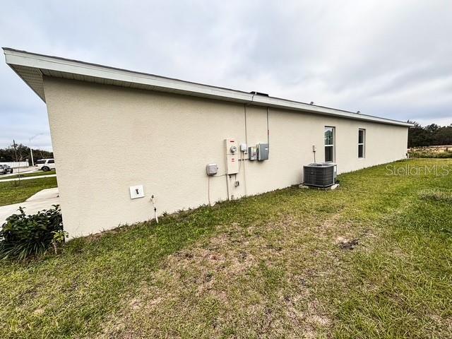 view of home's exterior with a yard, cooling unit, and stucco siding