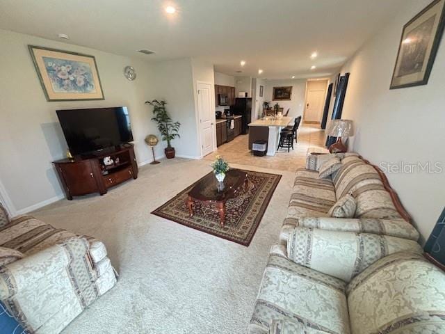 living room featuring recessed lighting, light carpet, and baseboards