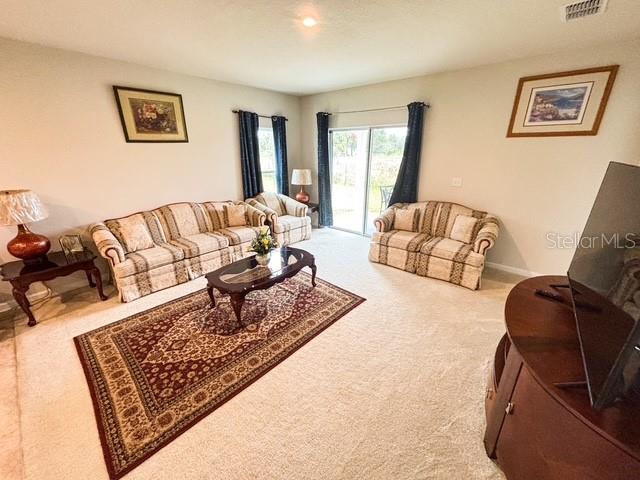 carpeted living area with visible vents and baseboards