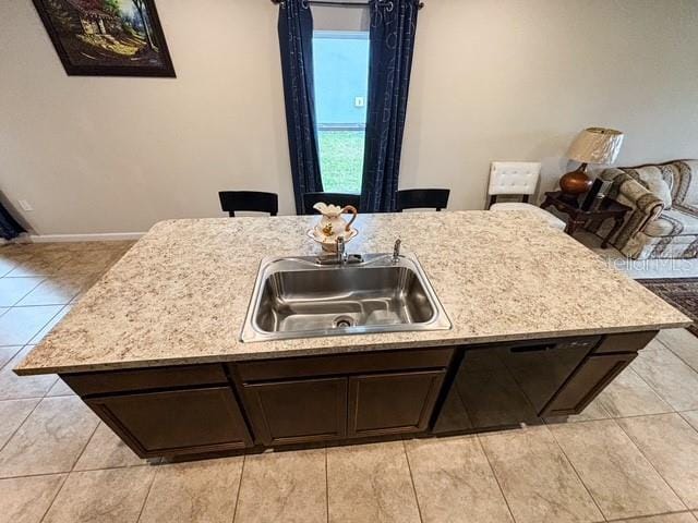 kitchen with light countertops, a sink, and dark brown cabinetry