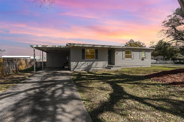 view of front of house with a carport, a front yard, driveway, and fence