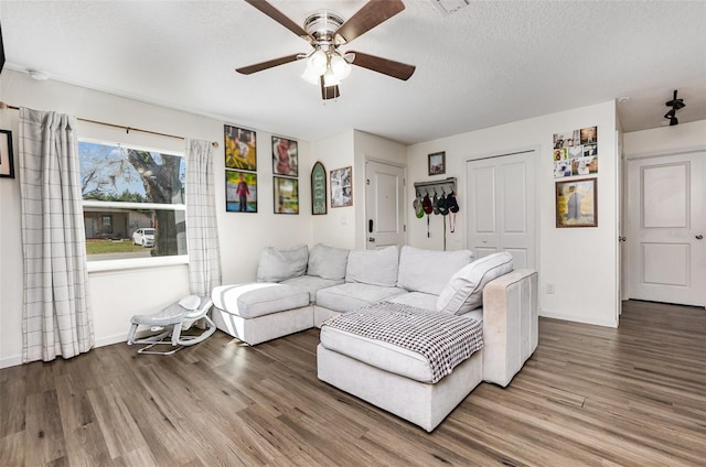 living room with a textured ceiling, wood finished floors, a ceiling fan, and baseboards