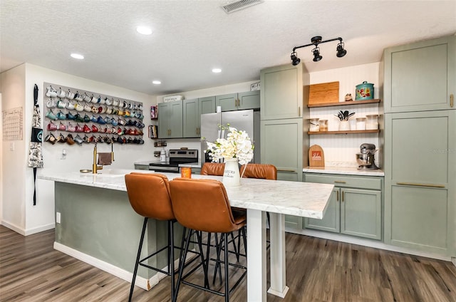 kitchen with a textured ceiling, dark wood-style flooring, visible vents, appliances with stainless steel finishes, and green cabinetry