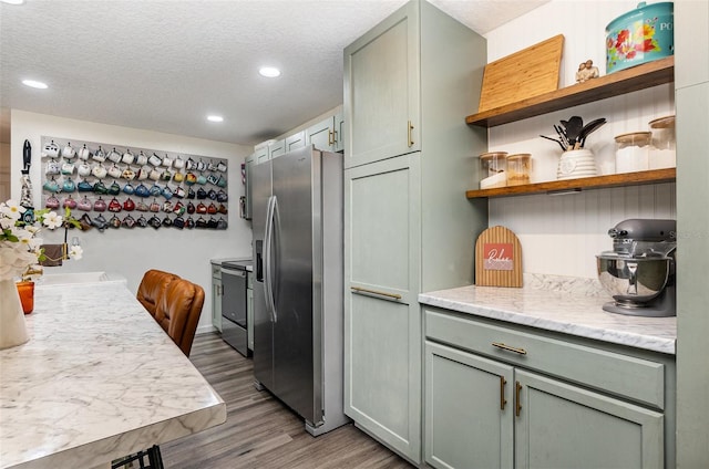 kitchen with appliances with stainless steel finishes, wood finished floors, a textured ceiling, open shelves, and recessed lighting