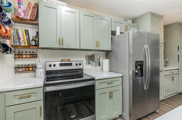 kitchen featuring green cabinets, light wood-style flooring, light stone counters, stainless steel appliances, and open shelves