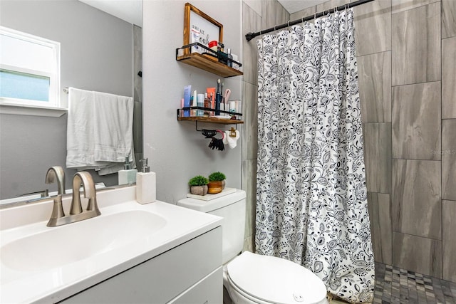 bathroom with toilet, a tile shower, and vanity