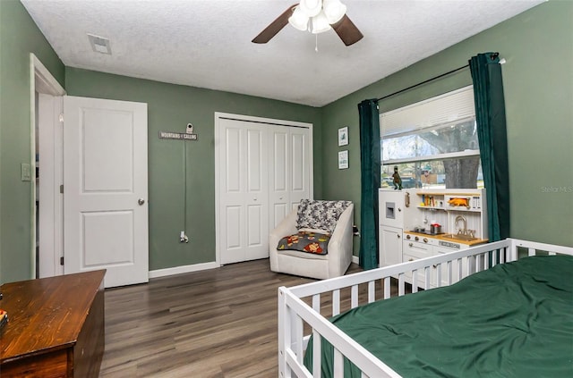 bedroom with baseboards, visible vents, wood finished floors, a textured ceiling, and a closet