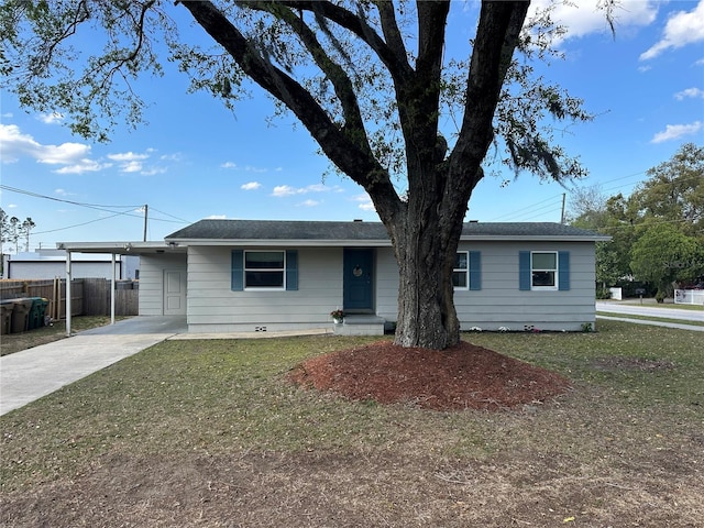 ranch-style home featuring an attached carport, driveway, a front lawn, and fence