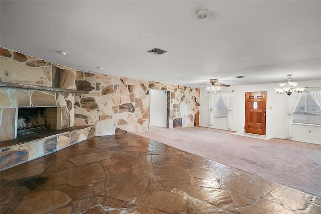 unfurnished living room featuring visible vents, stone flooring, carpet flooring, a fireplace, and ceiling fan with notable chandelier