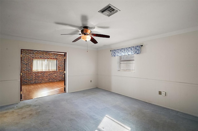 carpeted spare room featuring ceiling fan, visible vents, and ornamental molding