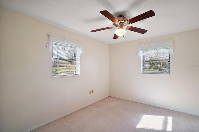 carpeted empty room featuring plenty of natural light, baseboards, and a ceiling fan