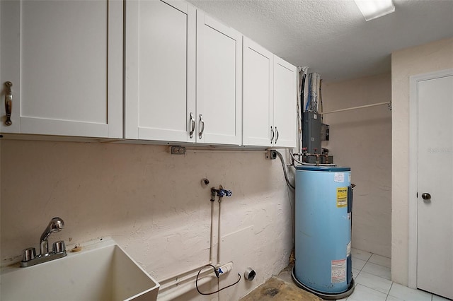 washroom featuring cabinet space, water heater, a sink, and a textured ceiling