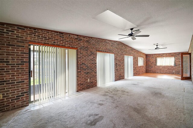 unfurnished living room with carpet, a textured ceiling, and brick wall