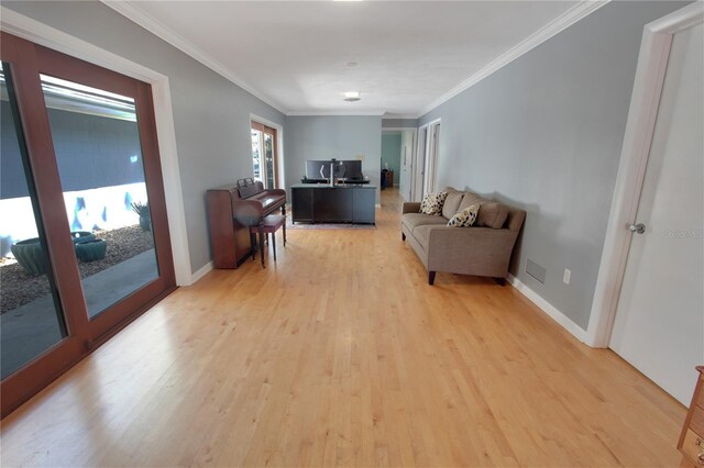 living room featuring baseboards, light wood-type flooring, and crown molding