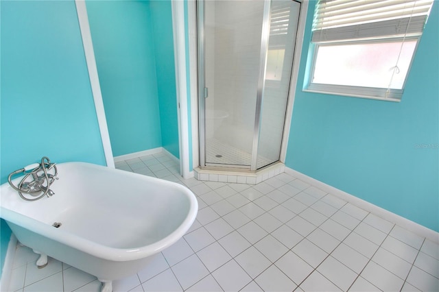 bathroom featuring a freestanding bath, baseboards, tile patterned flooring, and a shower stall