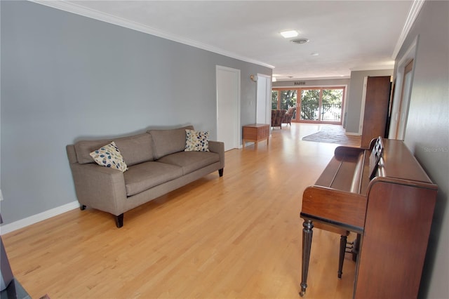 living area featuring baseboards, light wood-style flooring, and crown molding