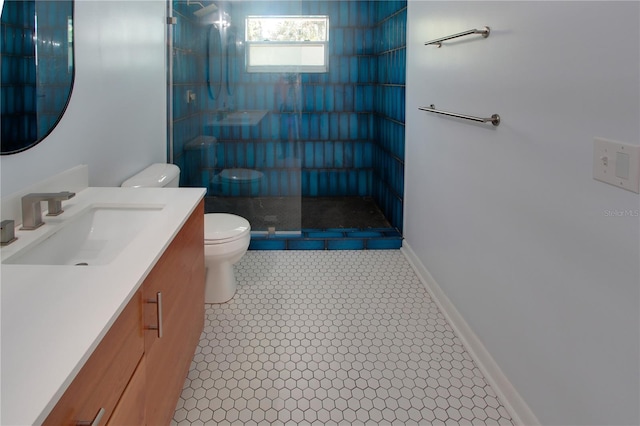 bathroom with tiled shower, vanity, toilet, and baseboards