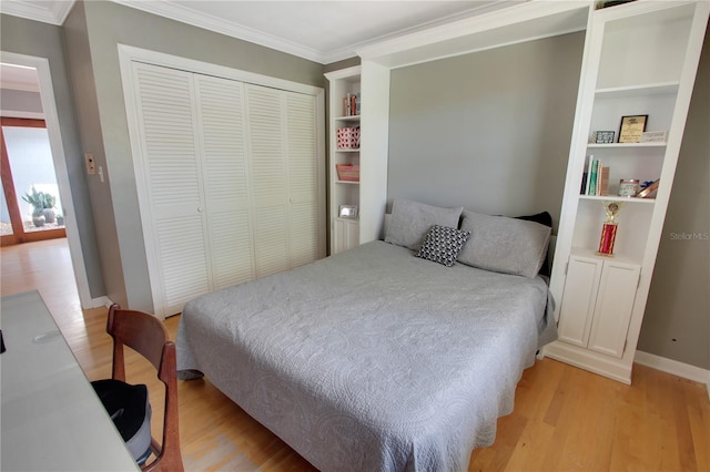 bedroom featuring light wood finished floors, baseboards, ornamental molding, and a closet