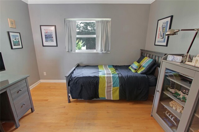 bedroom with light wood-type flooring, baseboards, and ornamental molding