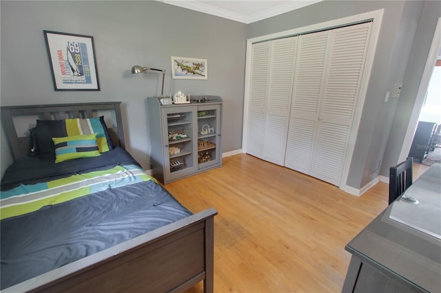 bedroom with a closet, crown molding, baseboards, and wood finished floors