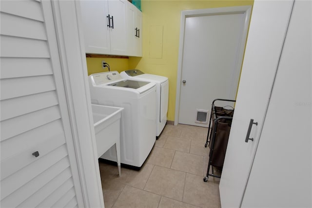 washroom featuring washer and dryer, cabinet space, and light tile patterned flooring