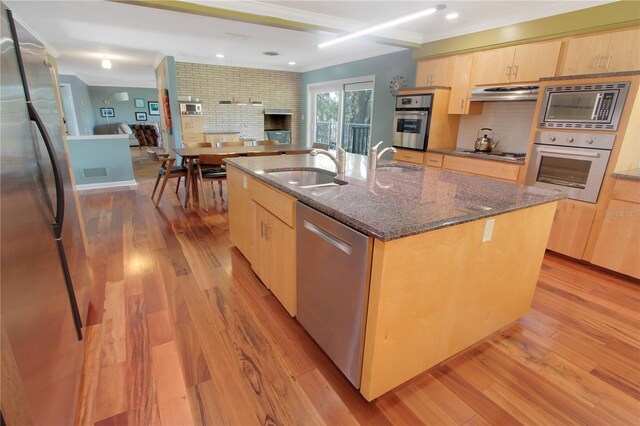 kitchen with stainless steel appliances, light wood-style flooring, light brown cabinetry, a sink, and under cabinet range hood