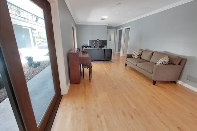 living area featuring visible vents, ornamental molding, light wood-style flooring, and baseboards