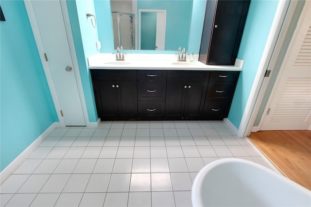 bathroom with a stall shower, a sink, baseboards, and double vanity