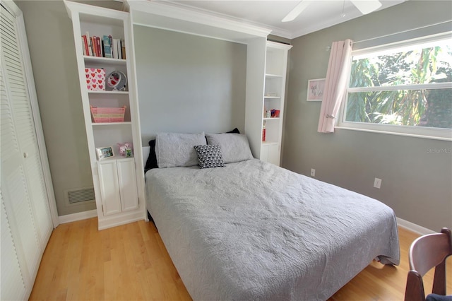 bedroom featuring light wood-type flooring, baseboards, visible vents, and crown molding