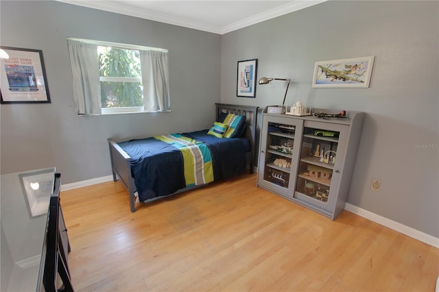 bedroom with baseboards, ornamental molding, and wood finished floors