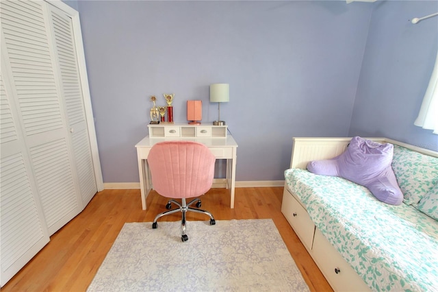 bedroom with a closet, baseboards, and wood finished floors