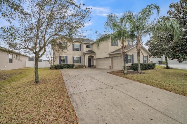 traditional-style home featuring driveway, a garage, fence, a front lawn, and stucco siding