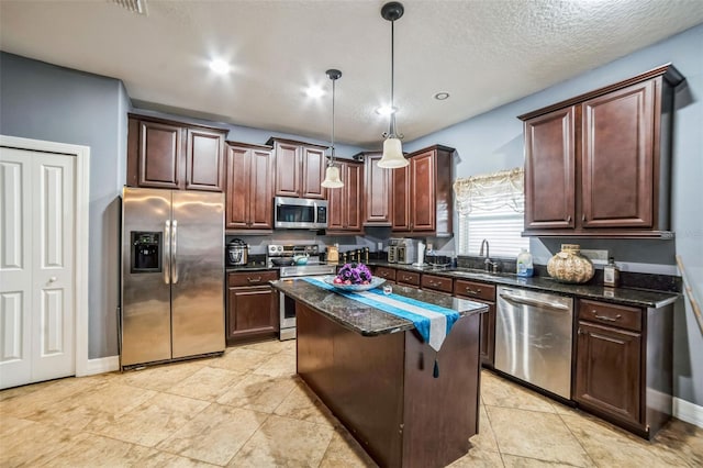 kitchen with dark brown cabinetry, appliances with stainless steel finishes, a center island, pendant lighting, and a sink