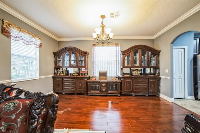 dining room with visible vents, arched walkways, dark wood-type flooring, crown molding, and a notable chandelier