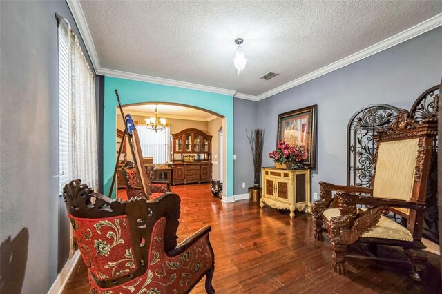 living area with arched walkways, visible vents, crown molding, and wood finished floors