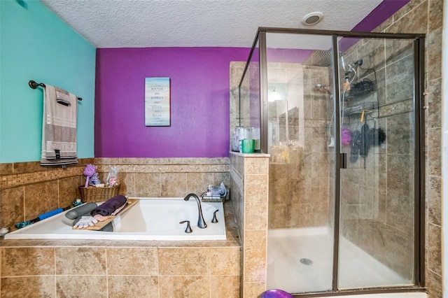 bathroom featuring a textured ceiling, a stall shower, and a garden tub