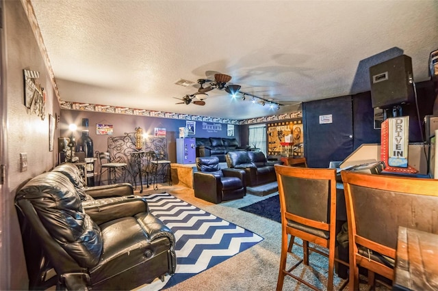 living area with visible vents, ceiling fan, rail lighting, carpet, and a textured ceiling