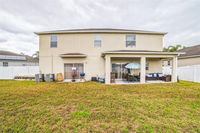 rear view of house with fence, a yard, a patio area, outdoor lounge area, and stucco siding