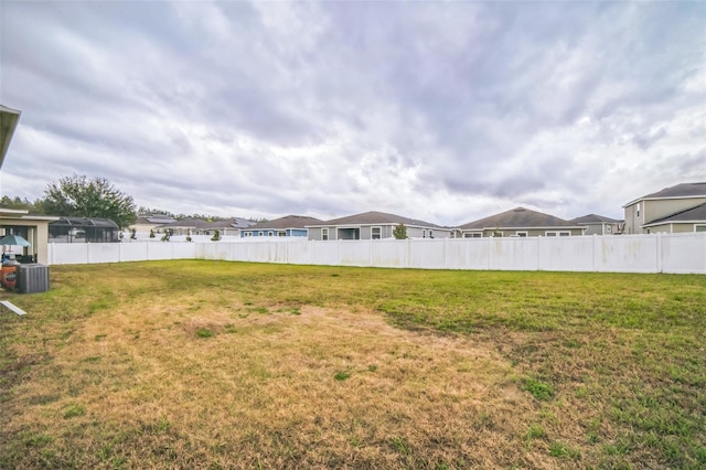 view of yard with central AC and fence