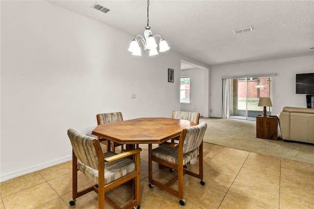 dining space featuring light tile patterned floors, a textured ceiling, visible vents, and light colored carpet